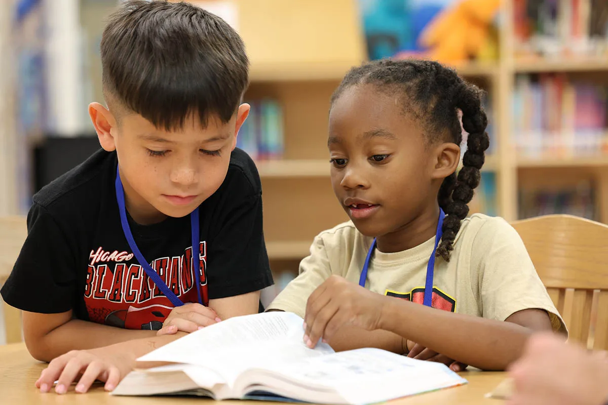 Two elementary students read a Bible lesson together during club.