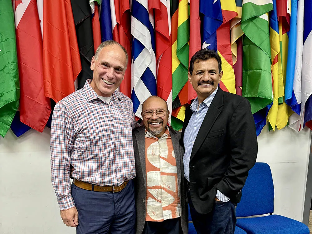 Matt Armstrong, Benjamin Vazquez, and Rolando Gonzalez stand in front of national flags.