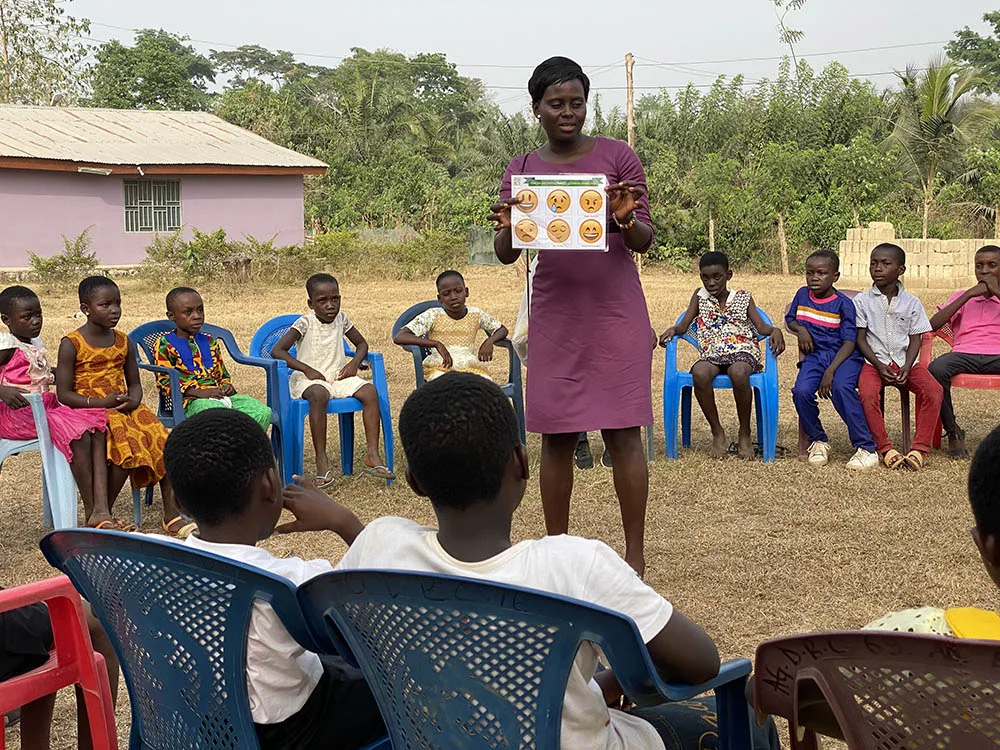 A woman teaches children during an outdoor Crossroads club.