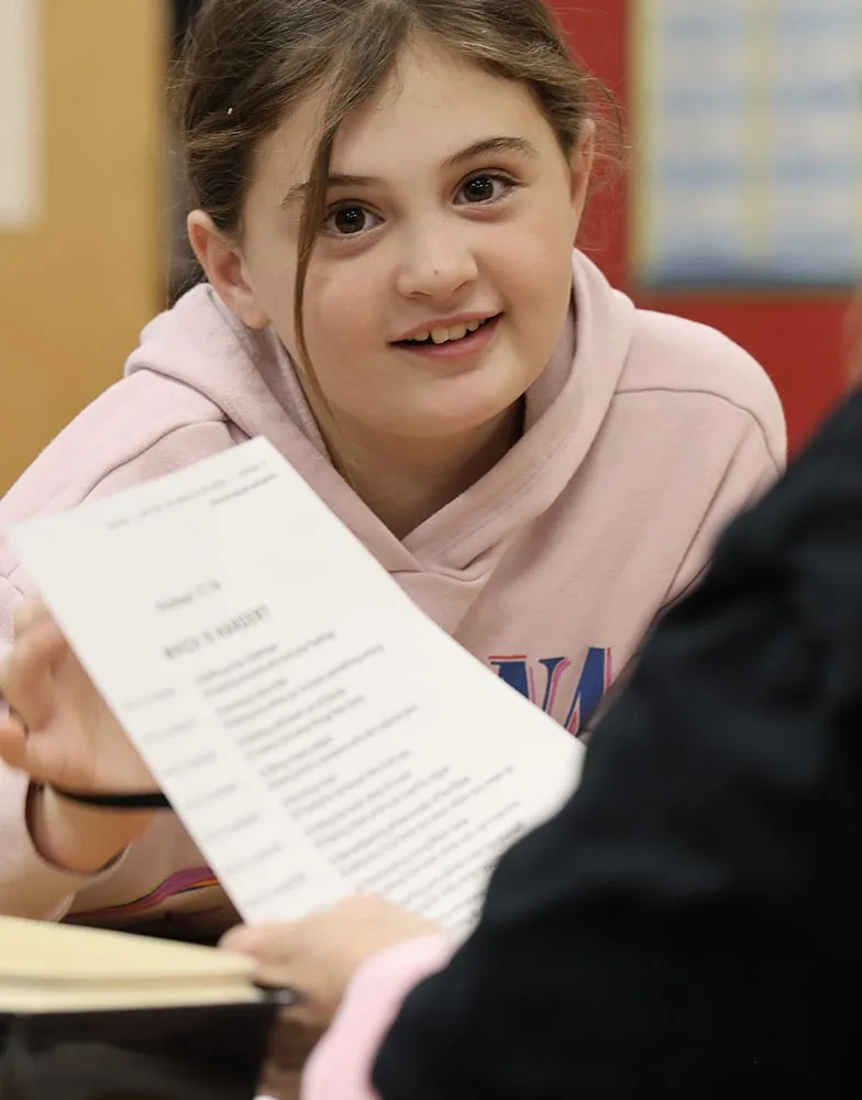 girl-in-kids-club A girl talks with an adult small-group leader while holding a lesson worksheet.