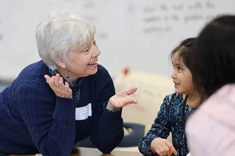 An adult volunteer talks with a child during a training activity.